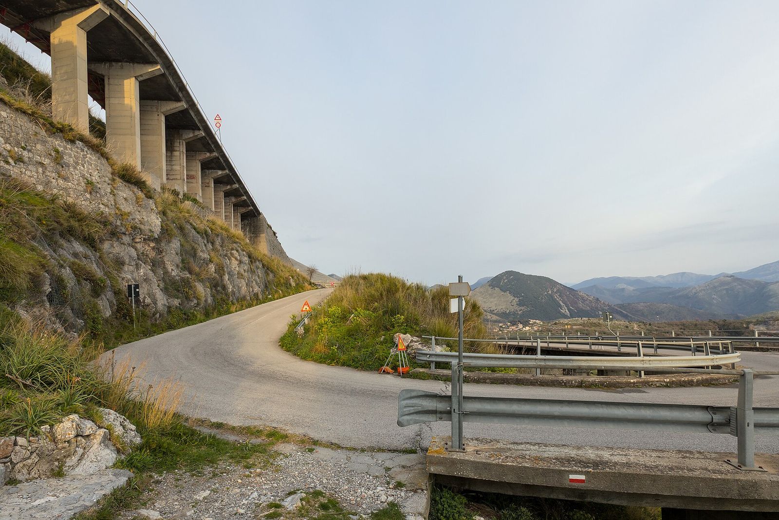 Una strada di montagna che curva sotto un viadotto, vicino a Maratea
