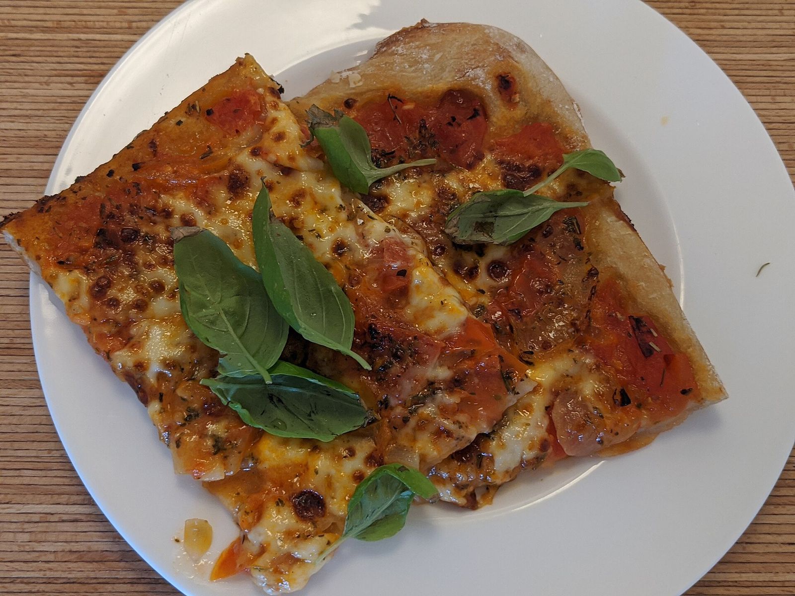 Una pizza margherita con basilico su un piatto bianco
