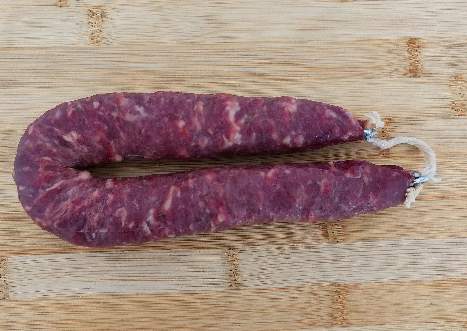 Una salsiccia lucanica stagionata su un tagliere di legno